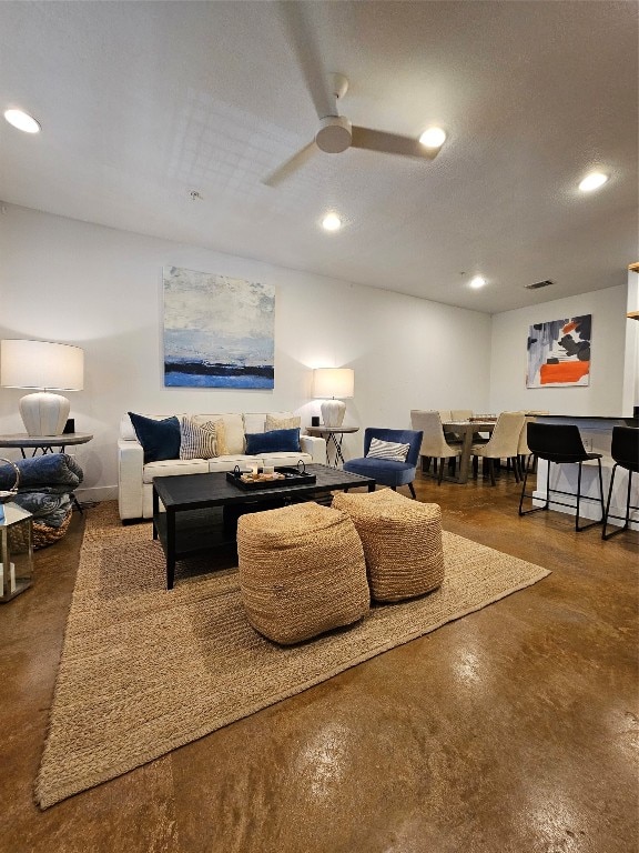 living room with concrete flooring, ceiling fan, and a textured ceiling