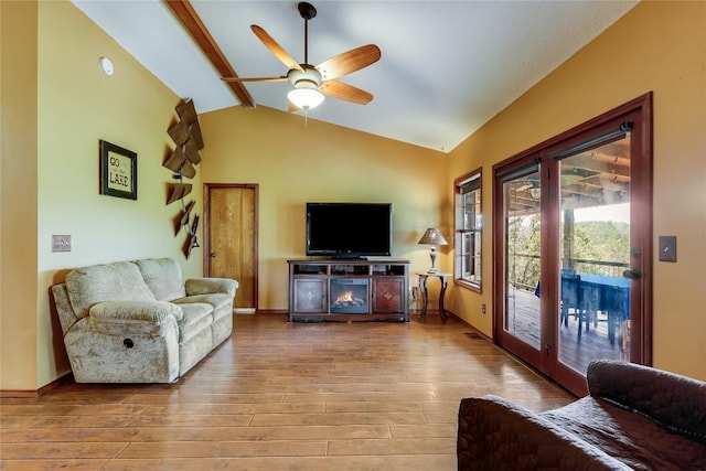 living room featuring ceiling fan, vaulted ceiling with beams, baseboards, and wood finished floors