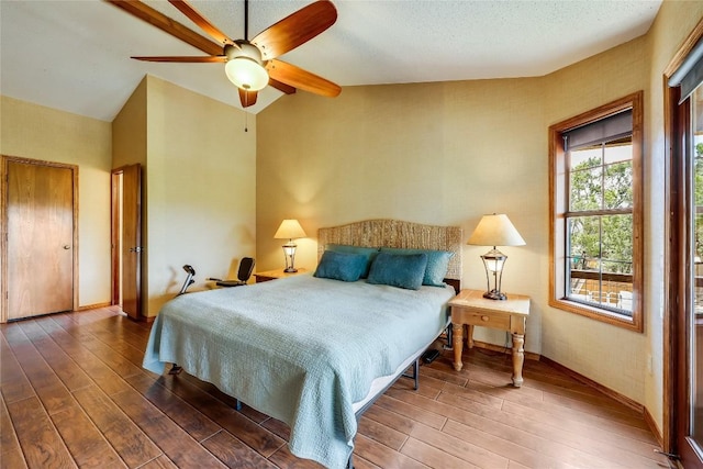 bedroom with vaulted ceiling, a textured ceiling, wood finished floors, and a ceiling fan