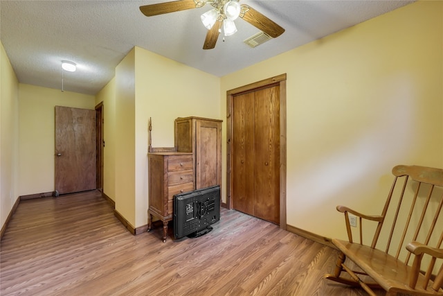 interior space featuring baseboards, visible vents, light wood-style flooring, ceiling fan, and a textured ceiling