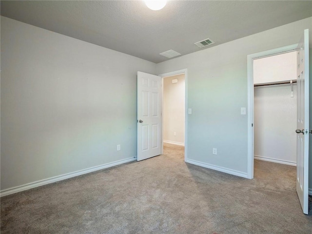 245 Tulum Ter, Leander, TX 78641 - unfurnished bedroom featuring a walk in closet, carpet, and a textured ceiling