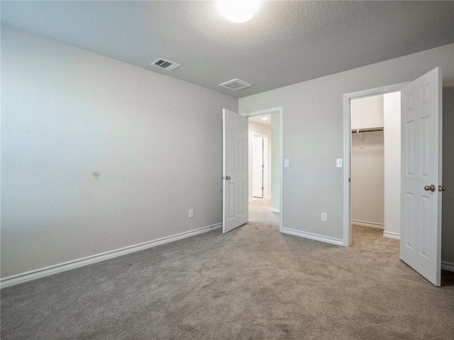 245 Tulum Ter, Leander, TX 78641 - unfurnished bedroom featuring a walk in closet, carpet floors, and a textured ceiling