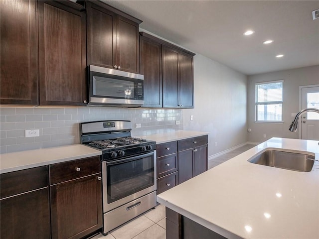 245 Tulum Ter, Leander, TX 78641 - kitchen featuring appliances with stainless steel finishes, light countertops, tasteful backsplash, dark brown cabinets, and recessed lighting
