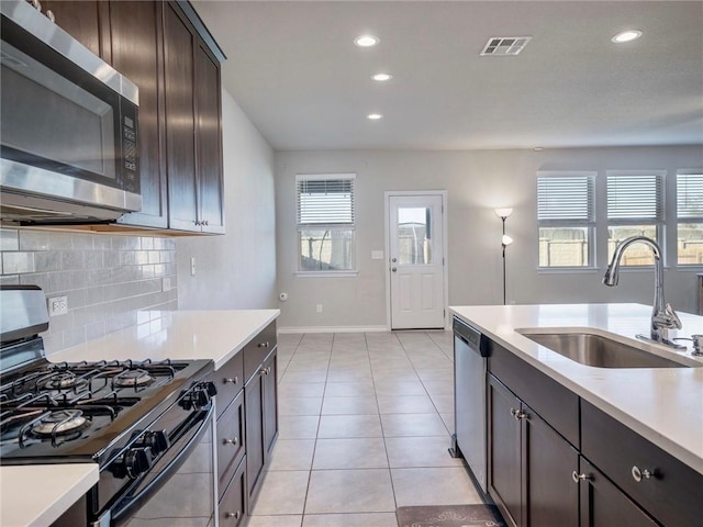 245 Tulum Ter, Leander, TX 78641 - kitchen with stainless steel appliances, light countertops, decorative backsplash, recessed lighting, and dark brown cabinets