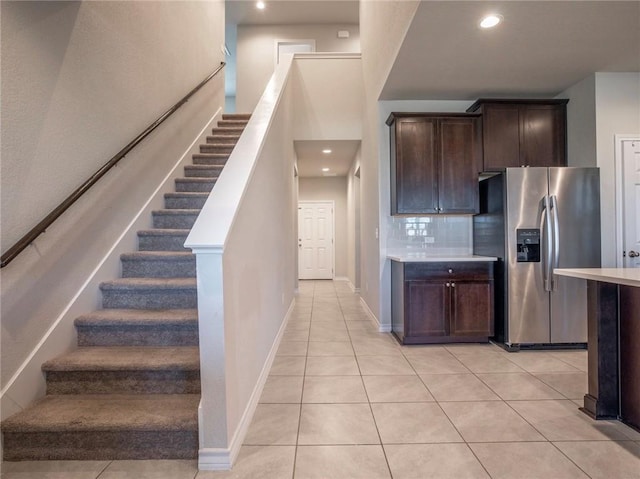 245 Tulum Ter, Leander, TX 78641 - kitchen with stainless steel refrigerator with ice dispenser, light tile patterned floors, dark brown cabinetry, decorative backsplash, and light countertops