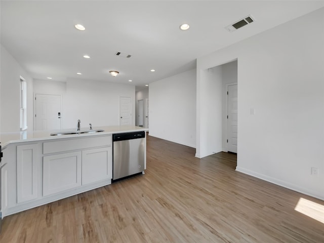 kitchen featuring white cabinetry, stainless steel dishwasher, sink, and light wood-type flooring