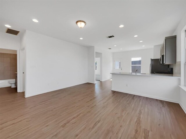 unfurnished living room with light hardwood / wood-style flooring and sink