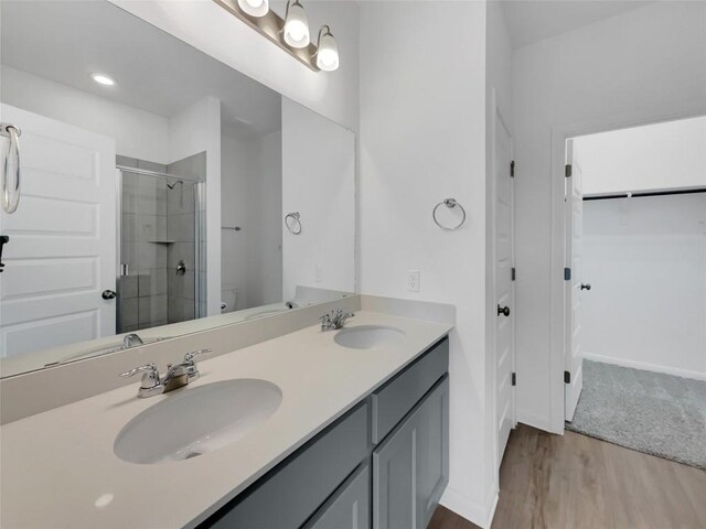 bathroom with double vanity, walk in shower, toilet, and wood-type flooring