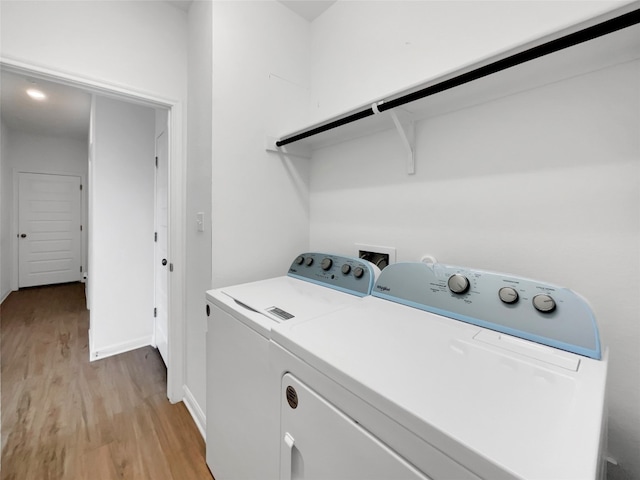 laundry area with separate washer and dryer and light hardwood / wood-style floors