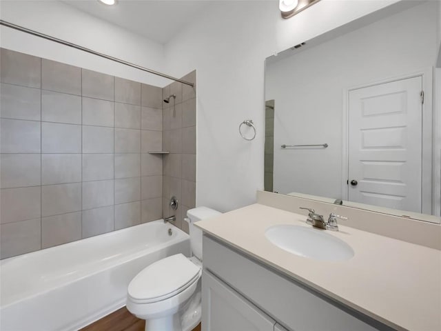 full bathroom featuring wood-type flooring, vanity, tiled shower / bath, and toilet