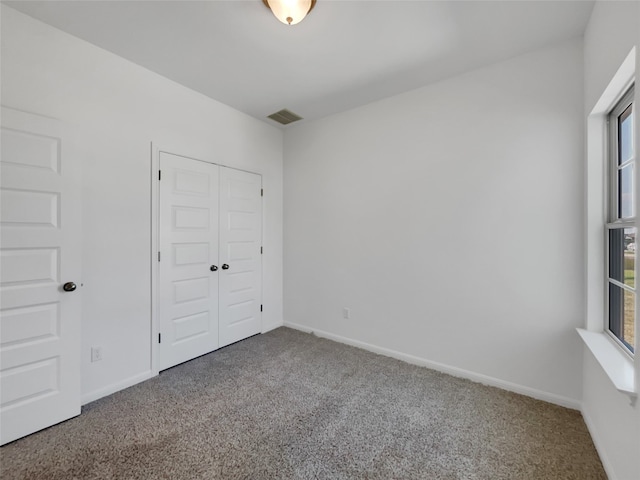 unfurnished bedroom featuring a closet, multiple windows, and carpet