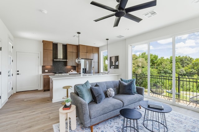 living room featuring ceiling fan, sink, and light hardwood / wood-style flooring