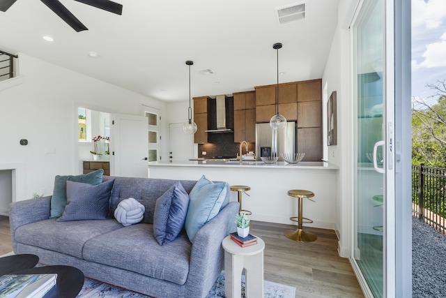 living room featuring ceiling fan, light hardwood / wood-style floors, and sink