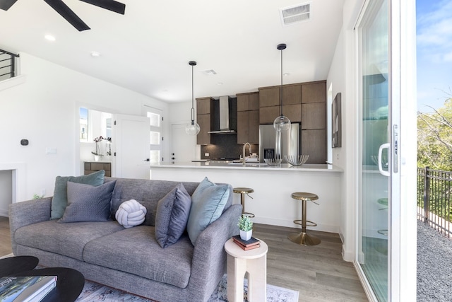 living room featuring ceiling fan, sink, and light hardwood / wood-style flooring