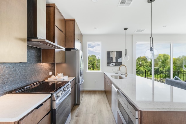 kitchen with wall chimney exhaust hood, pendant lighting, a wealth of natural light, and stainless steel appliances