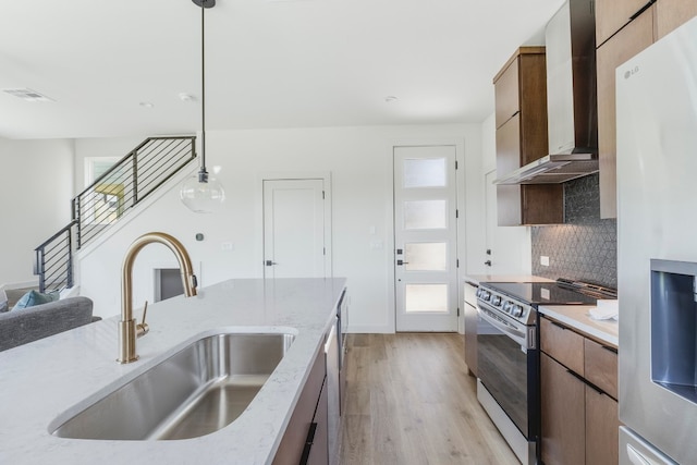 kitchen featuring light wood-type flooring, stainless steel range, decorative light fixtures, sink, and refrigerator with ice dispenser