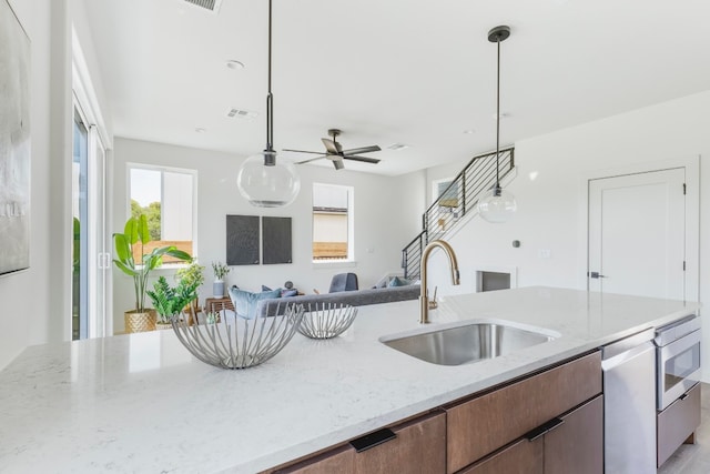 kitchen featuring decorative light fixtures, light stone countertops, sink, ceiling fan, and stainless steel dishwasher