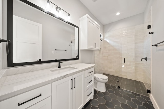 bathroom featuring tiled shower, vanity, toilet, and tile patterned flooring