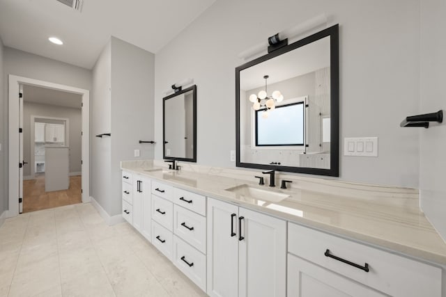 bathroom with hardwood / wood-style flooring, an inviting chandelier, and dual vanity