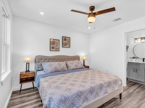 bedroom featuring ceiling fan, light hardwood / wood-style flooring, and connected bathroom