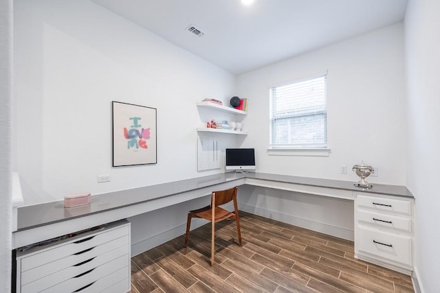 home office with wood finish floors, built in study area, visible vents, and baseboards