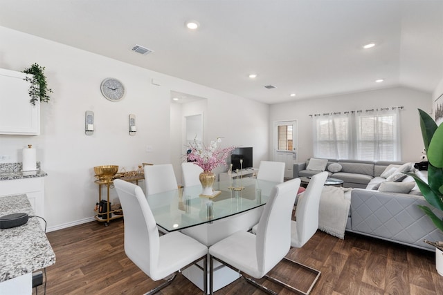 dining area with dark wood-type flooring and vaulted ceiling