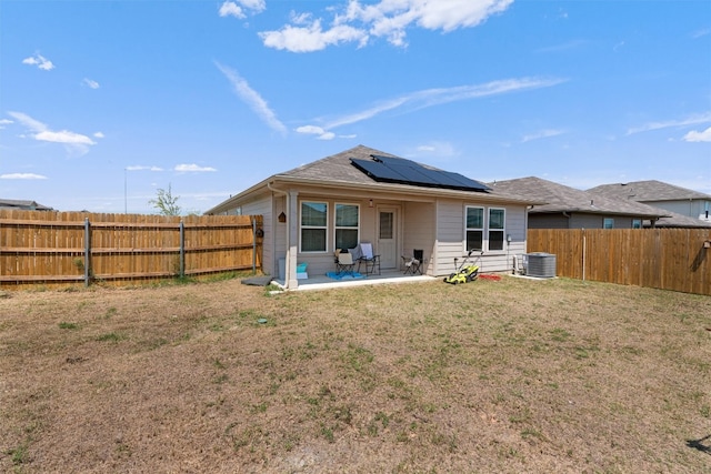 back of house featuring a yard, central AC, a patio area, and solar panels