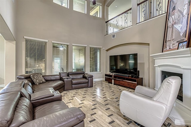 living room featuring a glass covered fireplace, baseboards, visible vents, and light wood finished floors