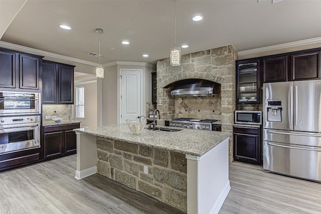 kitchen with visible vents, light stone countertops, ornamental molding, appliances with stainless steel finishes, and a sink