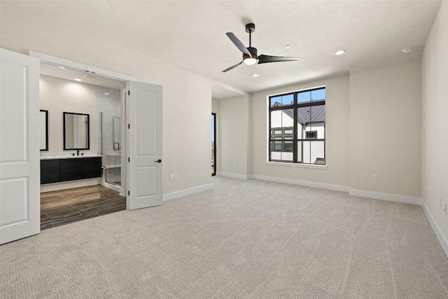 unfurnished bedroom featuring ensuite bath, ceiling fan, and light colored carpet