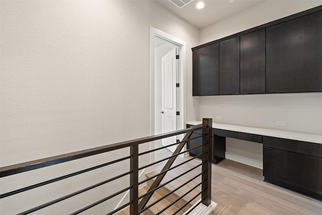 home office with light hardwood / wood-style flooring and built in desk