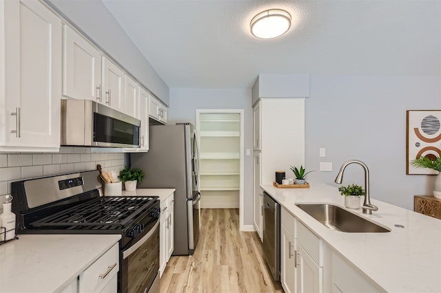 kitchen with sink, white cabinets, stainless steel appliances, and light hardwood / wood-style floors