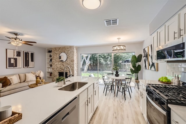 kitchen with white cabinets, decorative light fixtures, sink, and appliances with stainless steel finishes