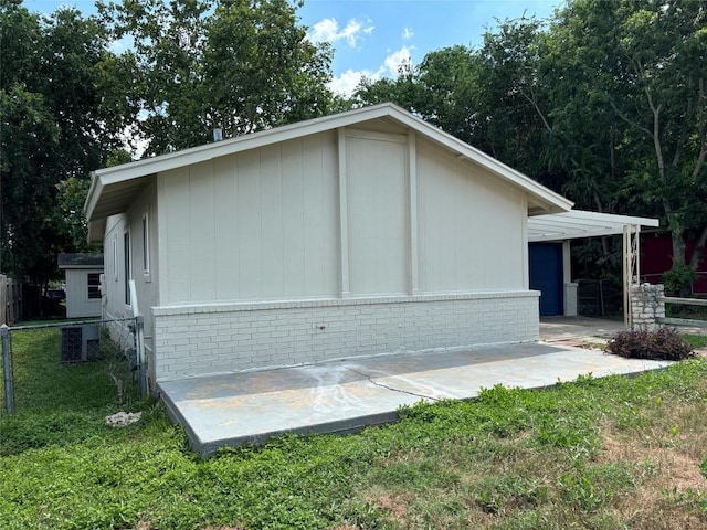view of side of home with brick siding, a yard, a patio area, and fence