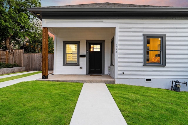 exterior entry at dusk featuring a lawn