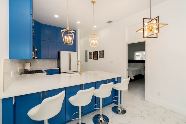 kitchen featuring blue cabinets, backsplash, high end white fridge, sink, and kitchen peninsula