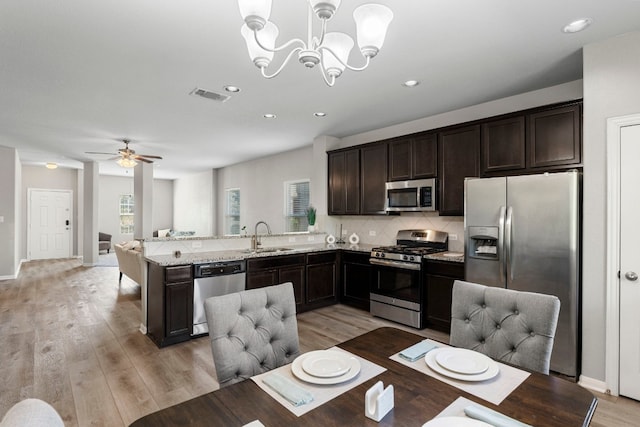 kitchen featuring pendant lighting, sink, light hardwood / wood-style floors, stainless steel appliances, and light stone countertops