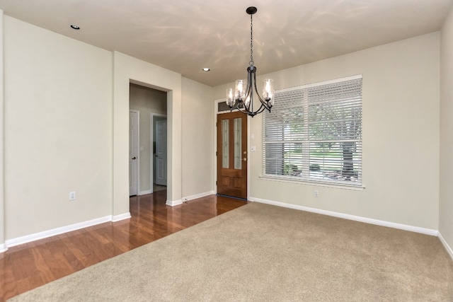 unfurnished room with a chandelier and carpet flooring