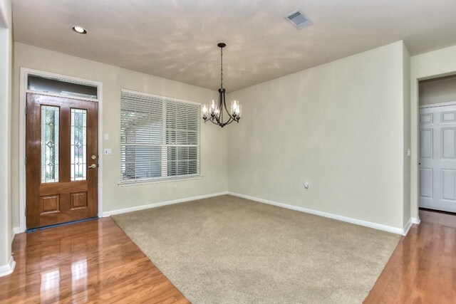 entryway with hardwood / wood-style flooring and a chandelier