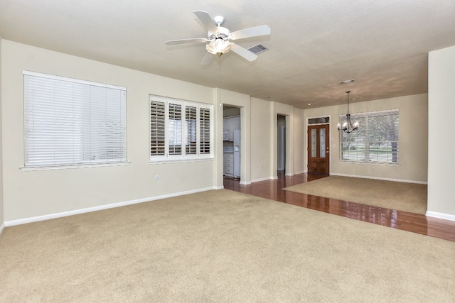 carpeted spare room with ceiling fan with notable chandelier