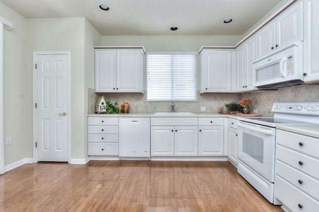 kitchen with sink, light wood-type flooring, white cabinetry, and white appliances