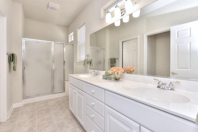 bathroom with walk in shower, dual bowl vanity, and tile patterned flooring