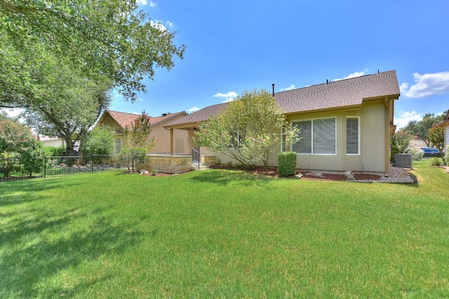 rear view of property featuring central air condition unit and a yard