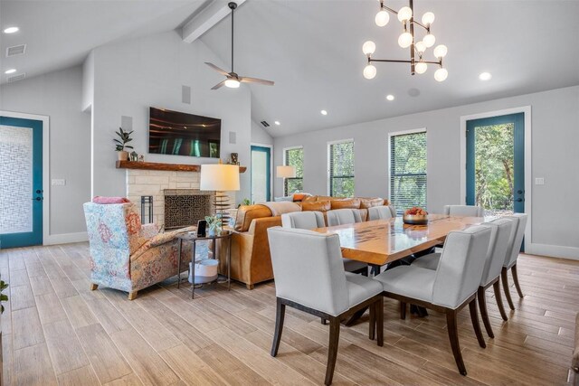 dining area featuring beamed ceiling, light hardwood / wood-style flooring, high vaulted ceiling, and a stone fireplace