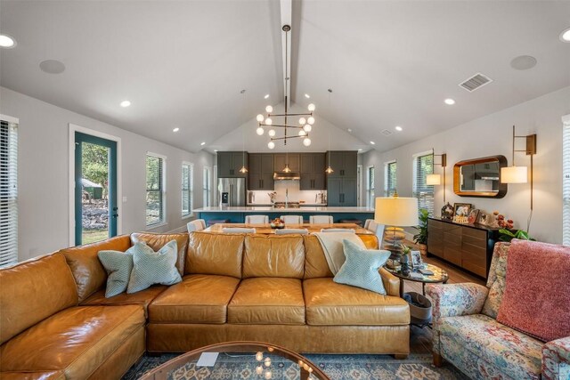 living room with a notable chandelier, high vaulted ceiling, and hardwood / wood-style flooring