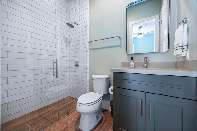 bathroom featuring a shower with door, vanity, and toilet