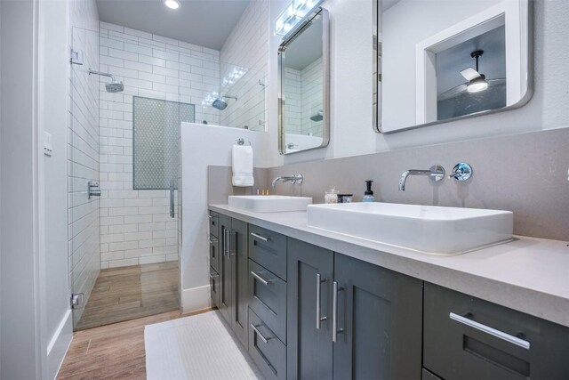 bathroom featuring dual bowl vanity, hardwood / wood-style flooring, and tiled shower