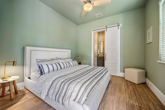 bedroom featuring ceiling fan, a barn door, radiator, and hardwood / wood-style flooring