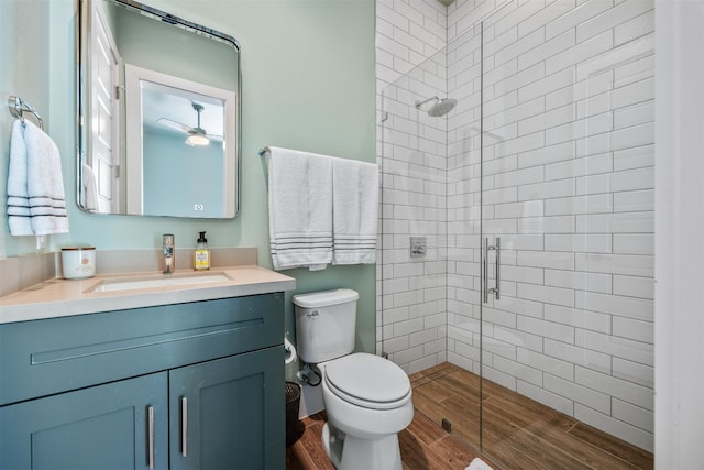 bathroom with ceiling fan, a shower with door, vanity, and toilet