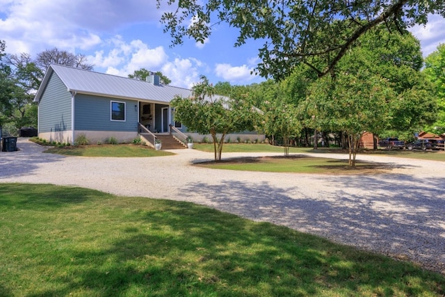 ranch-style house featuring a chimney, metal roof, and a front yard